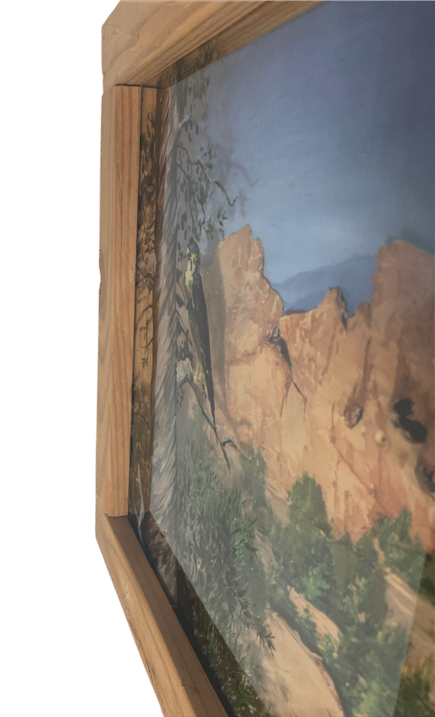Side view showing 3-D effect of hawk and tree, painted on the inside of the glass that sits away in a shadow-box effect from the background cliffs and sky.
